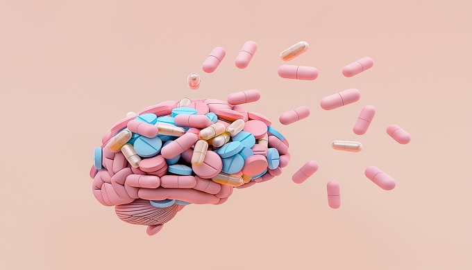 Brain with colorful pills isolated on pastel background.