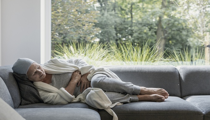 Weak elderly woman with cancer and stomach pain alone at home