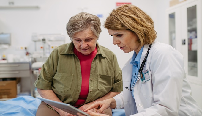 Geriatrician talking about test results with senior woman during check-up.
